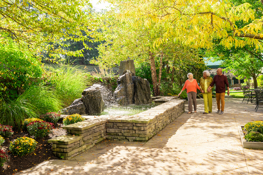 Group of three seniors walking on a patio near a waterfall